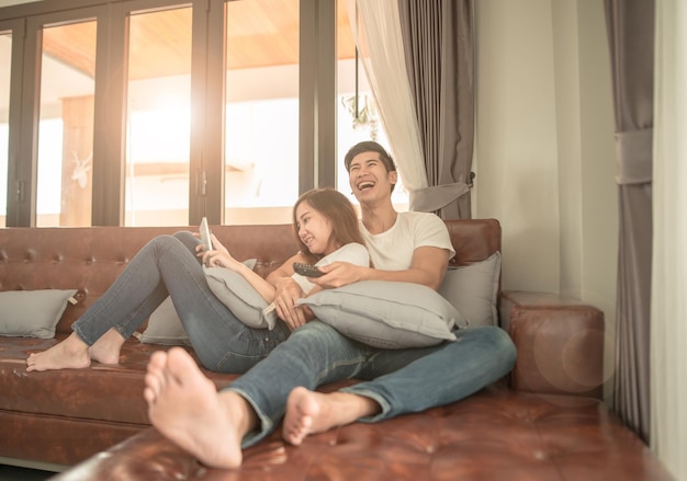 Photo happy young couple relaxing on sofa in hotel room