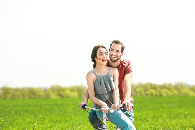 Happy young couple riding bicycle in countryside