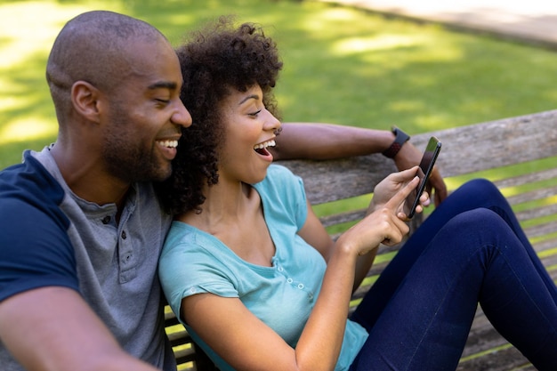 Happy young couple sitting on a bench in the garden