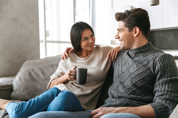 Happy young couple sitting on a couch at home, watching TV