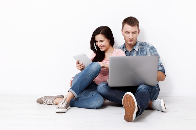 Happy young couple sitting on the floor with a laptop.