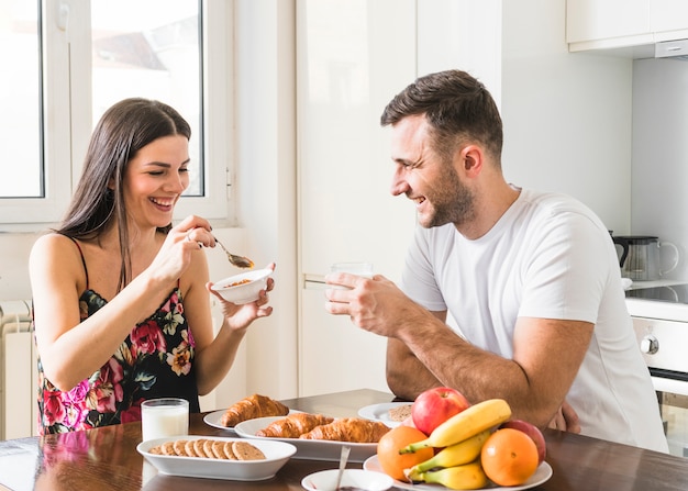 朝食をとって台所に座っている幸せな若いカップル