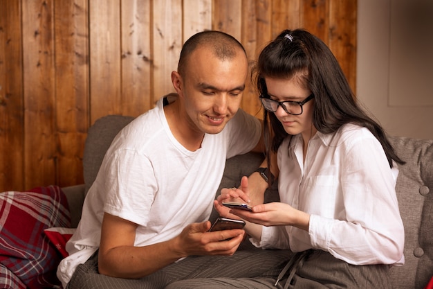 電話を見て一緒に座って幸せな若いカップル。ロマンチックなコンセプト。