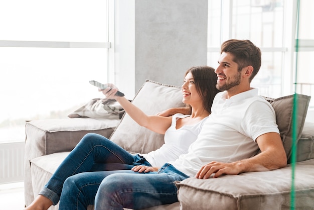 Happy young couple sitting and watching TV at home