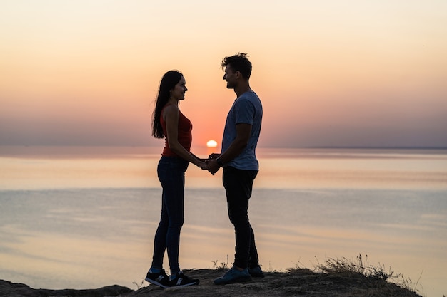 La giovane coppia felice in piedi sullo splendido sfondo del tramonto