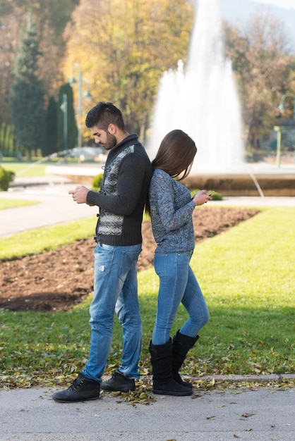 Happy Young Couple Standing Outdoors and Using Smartphone