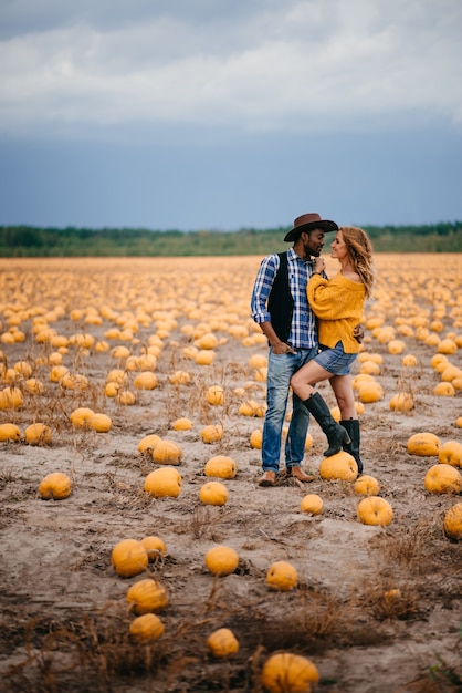 Happy young couple standing in a pumpkin field