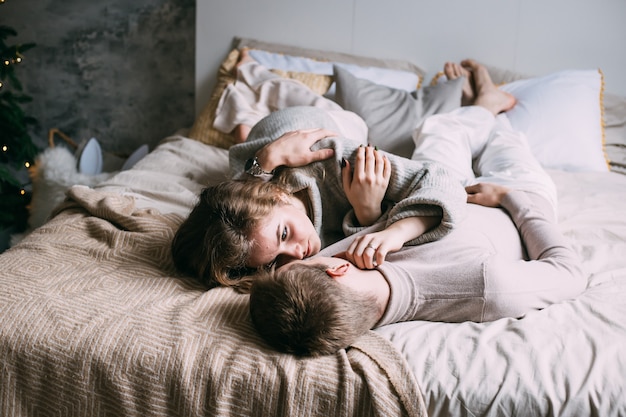 Happy young couple staying in bed at home