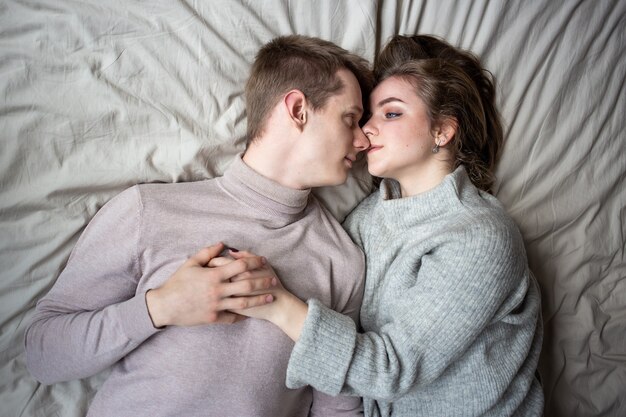 Happy young couple staying in bed at home