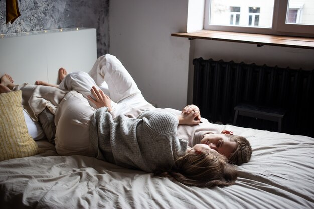 Happy young couple staying in bed at home