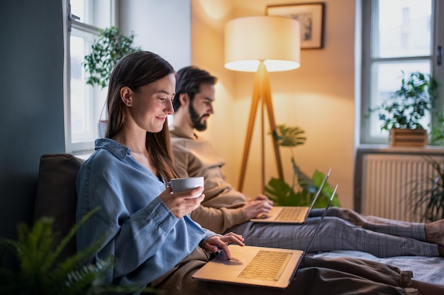 Photo happy young couple using laptops on bed indoors, home office in lockdown concept.