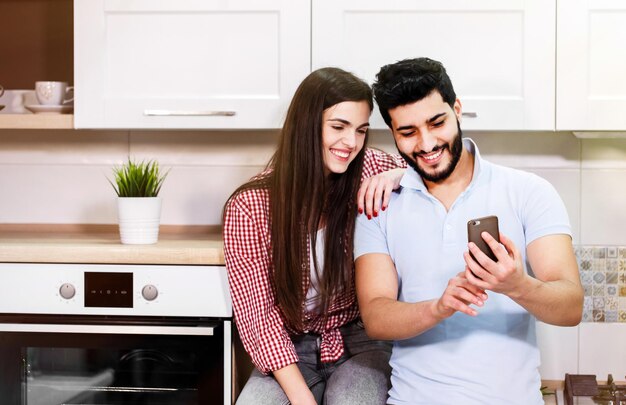 Happy young couple using smartphone wearing casual clothes spending time together