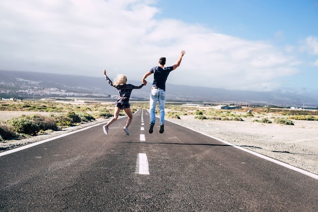 happy young couple walk together with love and friendship. forever life and positive vibes concept with logn way road and jump for happiness. family married style