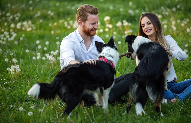 Photo happy young couple walking, playing with dogs in a park outdoor