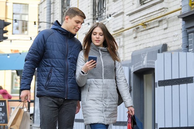 幸せな若いカップルが歩いて、春の街でのショッピング