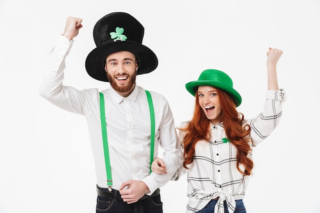 Photo happy young couple wearing costumes, celebrating stpatrick 's day isolated over white wall, having fun together