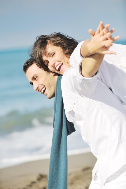 白い服を着た幸せな若いカップルは、休暇中の美しいビーチでロマンチックなレクリエーションと楽しみを持っています