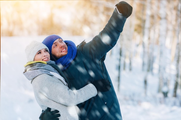 Happy young couple in winter park laughing and having fun family outdoors