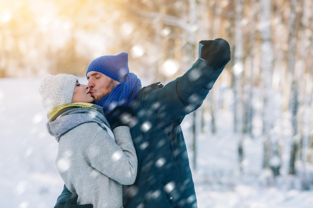 Happy young couple in winter park laughing and having fun family outdoors