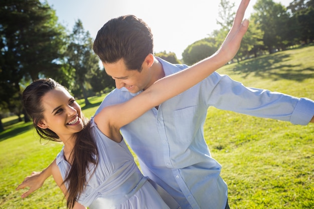 Happy young couple with arms outstretched at park