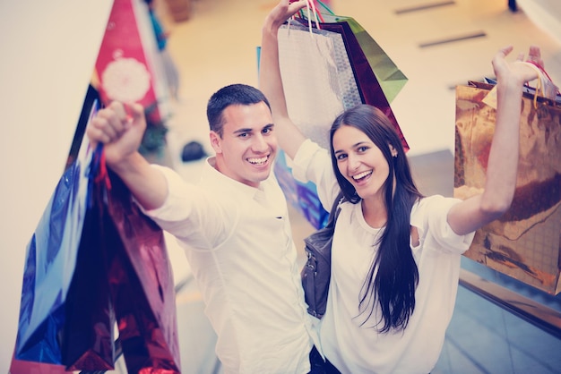 счастливая молодая пара с сумками в торговом центре