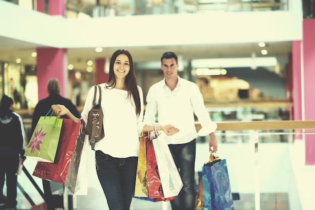 happy young couple with bags in shopping centre mall