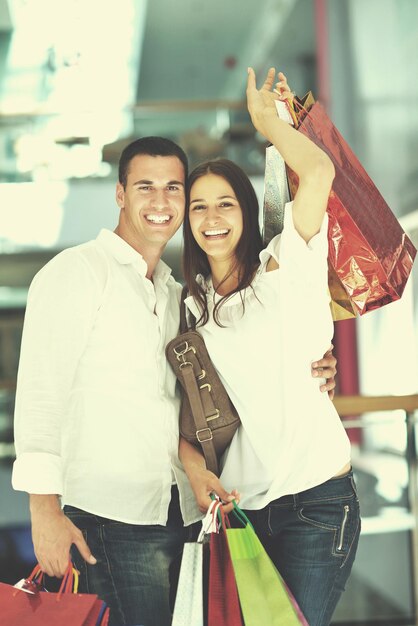 happy young couple with bags in shopping centre mall