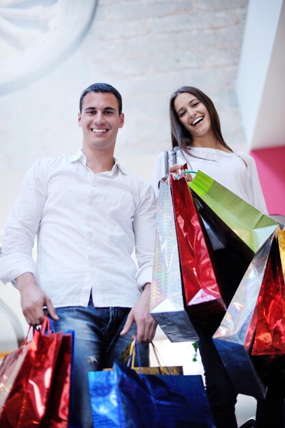 happy young couple with bags in shopping centre mall