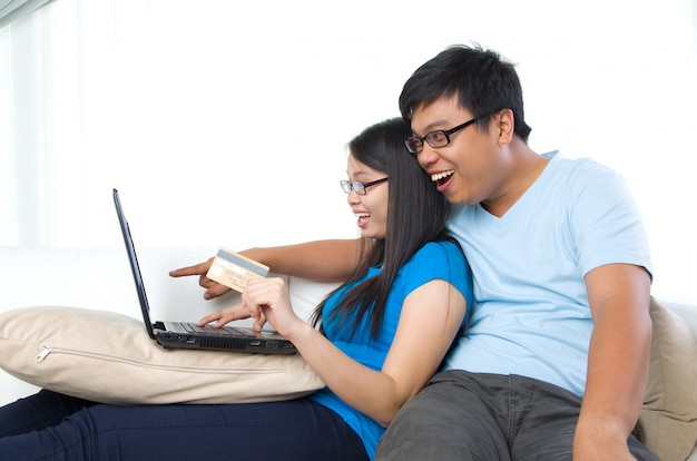 Happy young couple with credit card and laptop