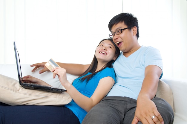 Happy young couple with credit card and laptop