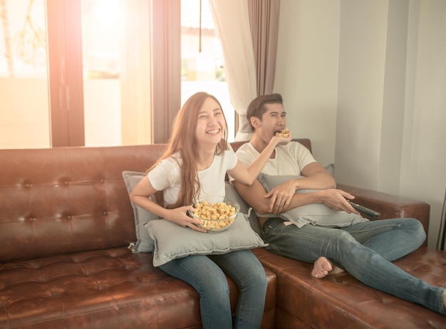 happy young couple with popcorns on sofa in hotel room