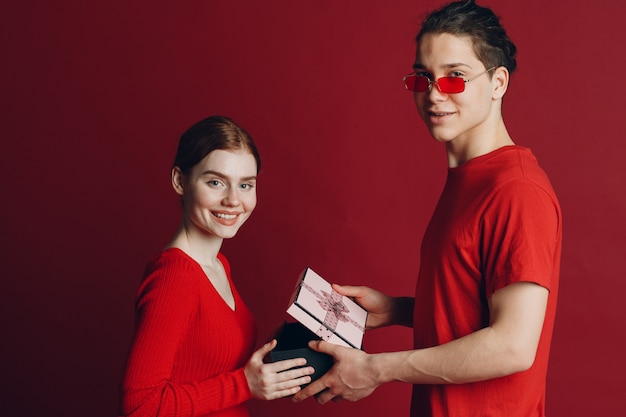 Happy Young Couple with a Present isolated on red background.