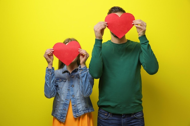 Happy young couple with red hearts on color background