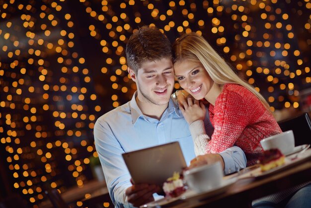 happy young couple with a tablet computer in restaurant