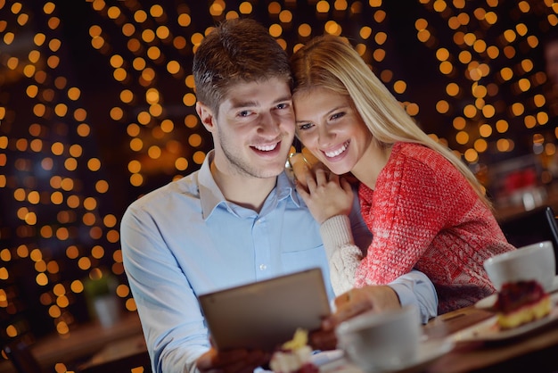 レストランでタブレット コンピューターと幸せな若いカップル