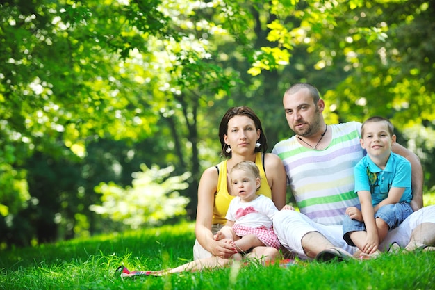 happy young couple with their children have fun at beautiful park outdoor in nature