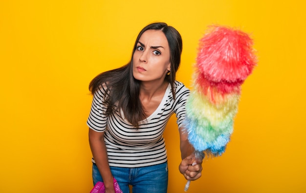 Happy young cute girl in casual wear is posing with some equipment and supply for house cleaning