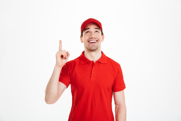 Happy young delivery man pointing isolated
