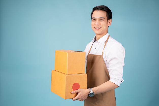 Happy young delivery man standing with parcel post box