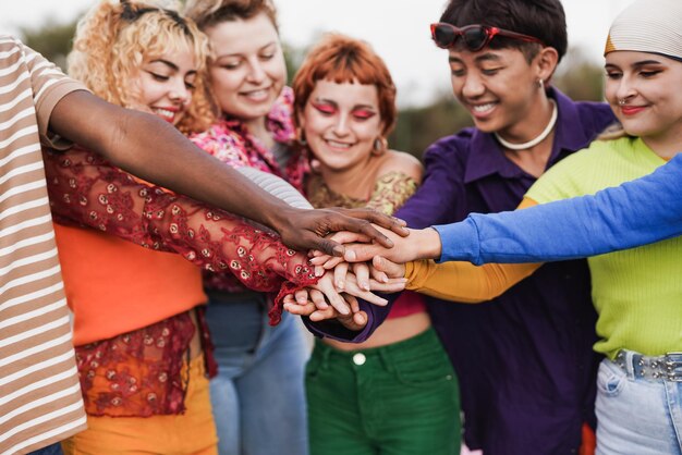 Happy young diverse people stacking hands outdoor