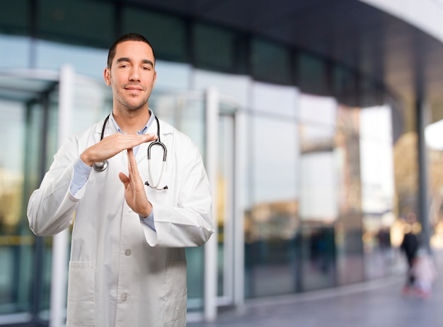 Felice giovane medico che fa un gesto di tempo di pausa