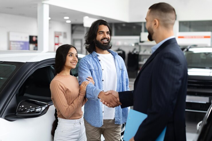 Photo happy young eastern couple buying new car at dealership salon