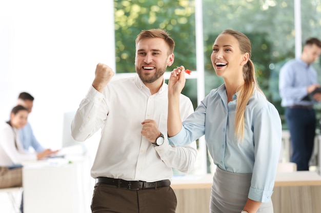 Happy young employees with dart in office