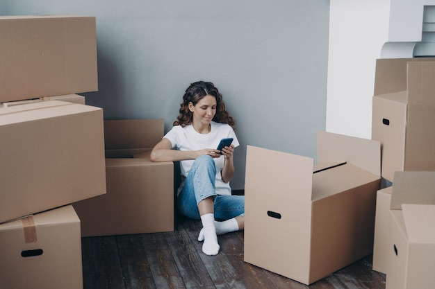 Happy young european woman with smartphone is packing boxes\
shipping service order concept