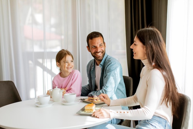 Happy young famila eat cakes and drink tea together in the room