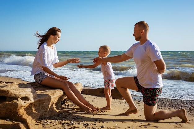 Foto felice giovane famiglia sulla spiaggia in riva al mare, divertendosi. concetto di vacanza in famiglia