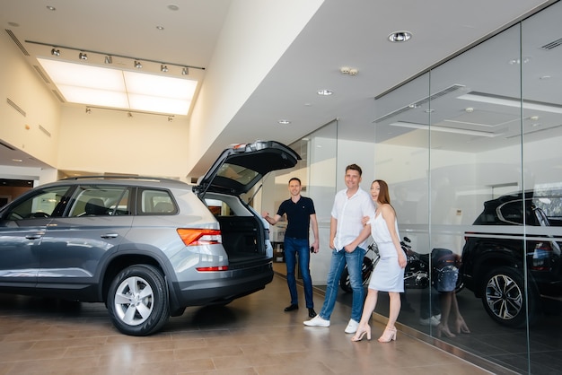 A happy young family chooses and buys a new car at a car dealership. Buying a new car.