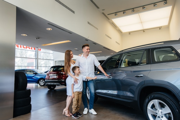 A happy young family chooses and buys a new car at a car dealership. Buying a new car.