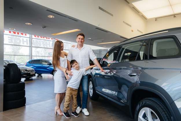 Happy young family chooses and buys a new car at a car dealership