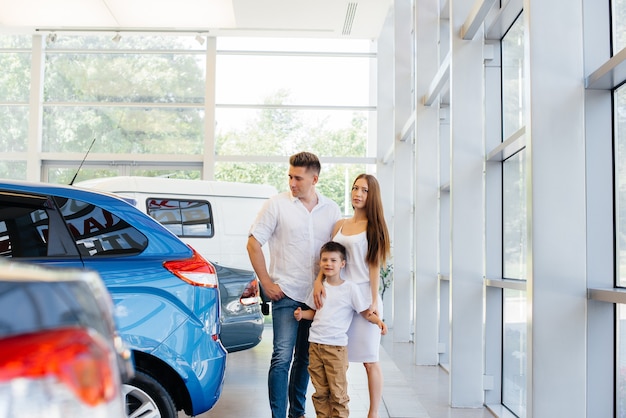 Happy young family chooses and buys a new car at a car dealership